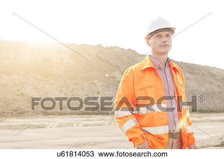 Stock Image - Thoughtful male supervisor looking away at construction site. Fotosearch