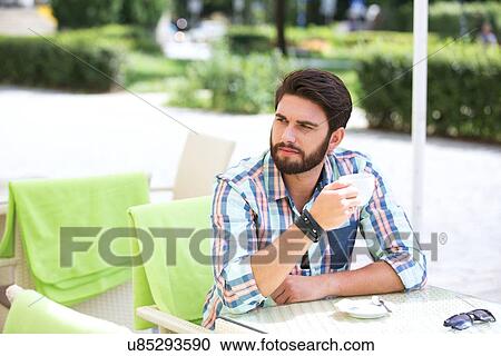 Thoughtful man holding coffee cup at sidewalk cafe View Large Photo Image Stock Image - Thoughtful man holding coffee cup at sidewalk cafe. Fotosearch