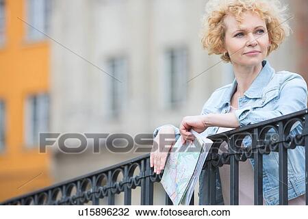 Thoughtful middle-aged woman holding map while leaning on railing View Large Photo Image Stock Image - Thoughtful middle-aged woman holding map while leaning on railing. Fotosearch