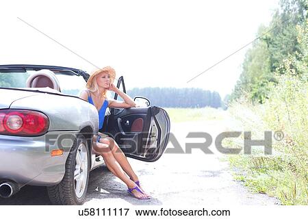 Thoughtful woman sitting in convertible on country road against clear sky View Large Photo Image Stock Photo - Thoughtful woman sitting in convertible on country road against clear sky. Fotosearch