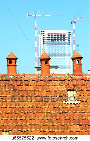Stock Image - Three old chimney pot with modern construction in the background. Fotosearch