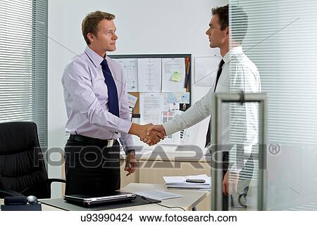 Two businessman shaking hands at office View Large Photo Image Picture - Two businessman shaking hands at office. Fotosearch