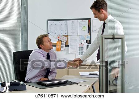 Two businessman shaking hands at office View Large Photo Image Stock Image - Two businessman shaking hands at office. Fotosearch