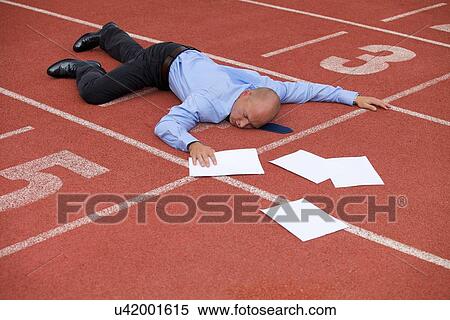 Stock Photography - View of a businessman lying on a race track. Fotosearch