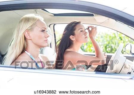 Woman doing make-up with female friend sitting in car View Large Photo Image Stock Image - Woman doing make-up with female friend sitting in car. Fotosearch