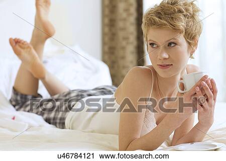 Stock Image - Woman drinking coffee in bed. Fotosearch
