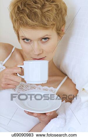 Woman drinking coffee in bed View Large Photo Image Stock Image - Woman drinking coffee in bed. Fotosearch