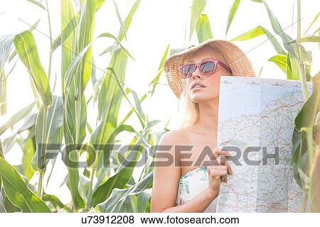 Woman holding map while standing amidst plants outdoors View Large Photo Image Stock Photo - Woman holding map while standing amidst plants outdoors. Fotosearch