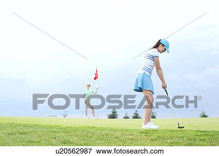 Woman playing golf with female friend against sky View Large Photo Image Stock Photo - Woman playing golf with female friend against sky. Fotosearch