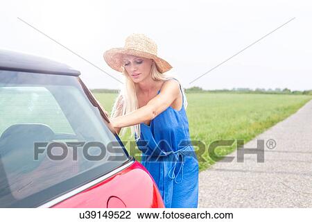 Woman pushing broken down car on country road against clear sky View Large Photo Image Stock Image - Woman pushing broken down car on country road against clear sky. Fotosearch