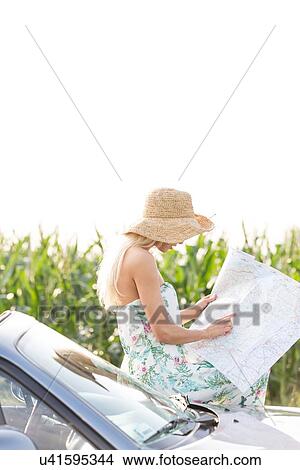 Woman reading map while leaning on convertible against clear sky View Large Photo Image Picture - Woman reading map while leaning on convertible against clear sky. Fotosearch