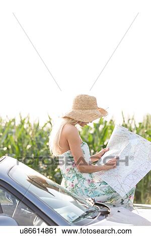 Woman reading map while leaning on convertible View Large Photo Image Stock Image - Woman reading map while leaning on convertible. Fotosearch