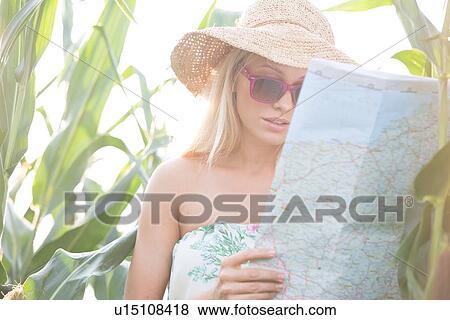 Stock Photo - Woman reading map while standing amidst plants outdoors. Fotosearch