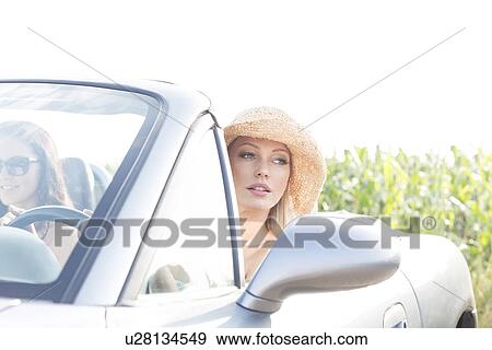 Woman sitting in convertible with female friend on sunny day View Large Photo Image Stock Photo - Woman sitting in convertible with female friend on sunny day. Fotosearch