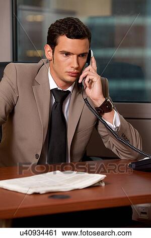 Young businessman talking on telephone in office View Large Photo Image Stock Image - Young businessman talking on telephone in office. Fotosearch