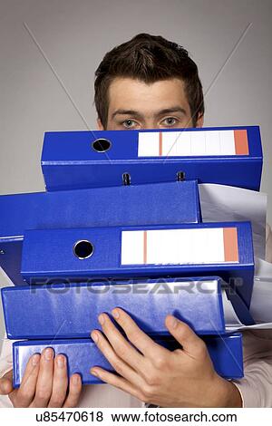 Young caucasian businessman holding a stack of binders View Large Photo Image Stock Photo - Young caucasian businessman holding a stack of binders. Fotosearch