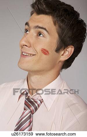 Stock Photo - Young caucasian businessman with lipstick kiss mark on his cheek. Fotosearch