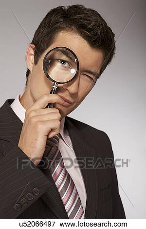 Stock Photo - Young caucasian businessman with magnifying glass. Fotosearch