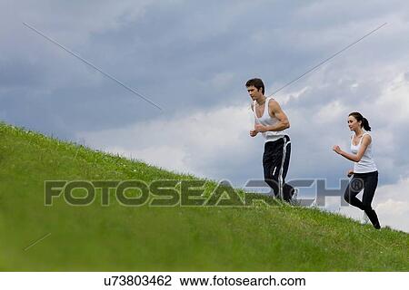 Stock Image - Young couple exercising in park. Fotosearch
