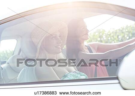 Stock Image - Young female friends in car on sunny day. Fotosearch