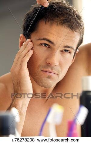 Stock Photo - Young man combing his hair. Fotosearch
