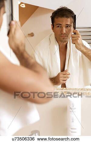 Young man combing his hair View Large Photo Image Stock Photograph - Young man combing his hair. Fotosearch