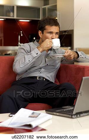 Young man drinking tea, sitting in sofa View Large Photo Image Stock Image - Young man drinking tea, sitting in sofa. Fotosearch