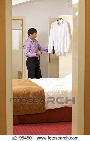 Young man holding tie in hotel room View Large Photo Image Stock Image - Young man holding tie in hotel room. Fotosearch