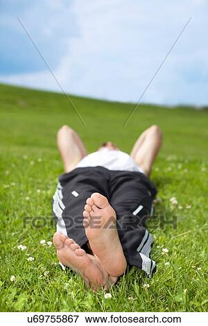 Young man lying on grass in park View Large Photo Image Stock Photo - Young man lying on grass in park. Fotosearch