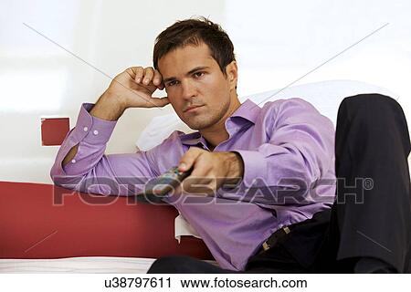 Young man on bed using remote control View Large Photo Image Stock Image - Young man on bed using remote control. Fotosearch
