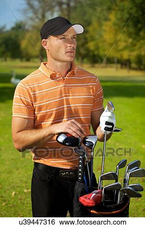 Young man standing by golf bag full of sticks View Large Photo Image Stock Photograph - Young man standing by golf bag full of sticks. Fotosearch