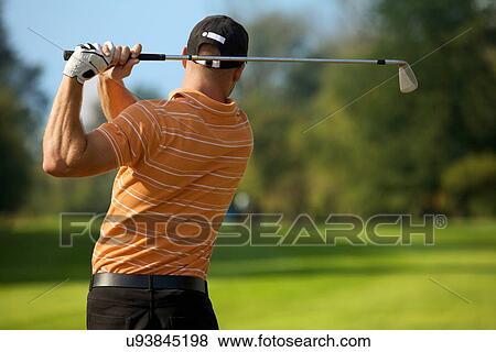 Young man swinging golf club, rear view View Large Photo Image Stock Photo - Young man swinging golf club, rear view. Fotosearch