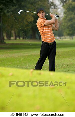 Young man swinging golf club View Large Photo Image Stock Image - Young man swinging golf club. Fotosearch