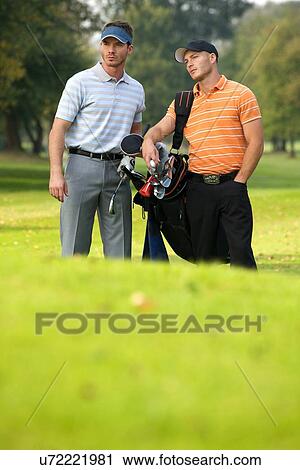 Young men standing on golf course carrying bags View Large Photo Image Stock Image - Young men standing on golf course carrying bags. Fotosearch