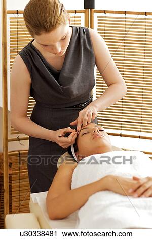 Stock Image - Young woman having eye-brows plucked. Fotosearch