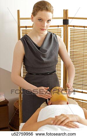 Stock Photograph - Young woman receiving facial treatment in spa. Fotosearch