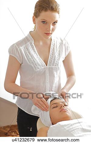 Young woman receiving head massage from masseuse View Large Photo Image Stock Photo - Young woman receiving head massage from masseuse. Fotosearch