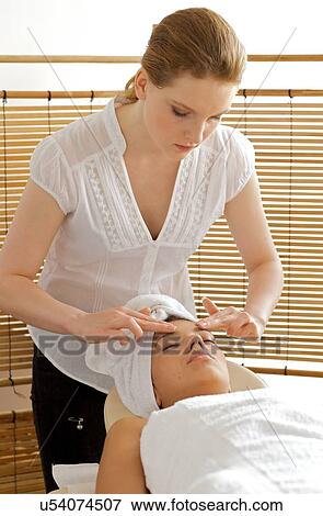Young woman receiving head massage from masseuse View Large Photo Image Stock Photo - Young woman receiving head massage from masseuse. Fotosearch