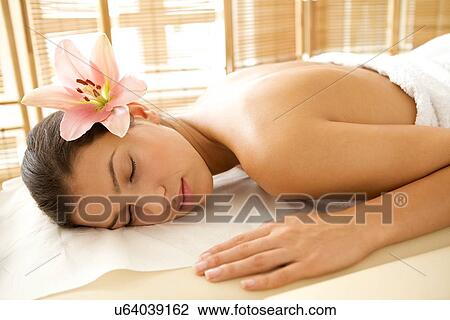 Stock Image - Young woman relaxing on massage table, eyes closed. Fotosearch