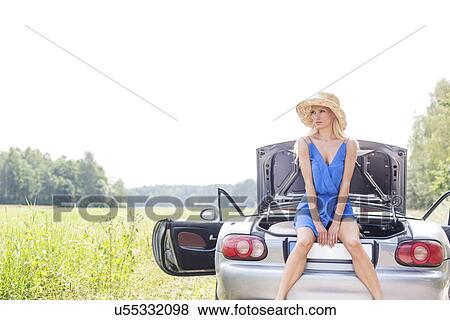 Young woman sitting on convertible trunk against clear sky View Large Photo Image Stock Photo - Young woman sitting on convertible trunk against clear sky. Fotosearch