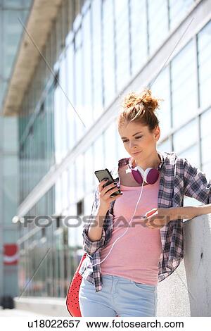 Young woman using smart phone outside office building View Large Photo Image Stock Photo - Young woman using smart phone outside office building. Fotosearch