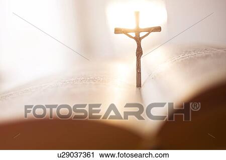 Stock Image - Backlit cross in open Bible. Fotosearch