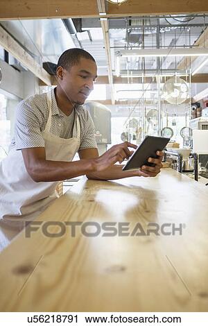 Stock Image - Bakery owner using digital tablet. Fotosearch