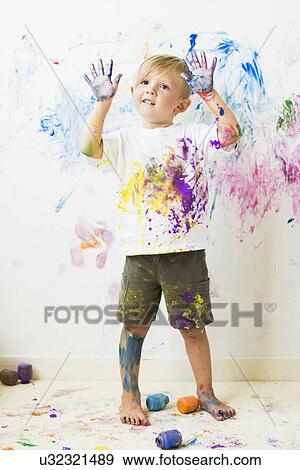 Stock Photo - Boy (2-3) showing hands after painting on wall. Fotosearch