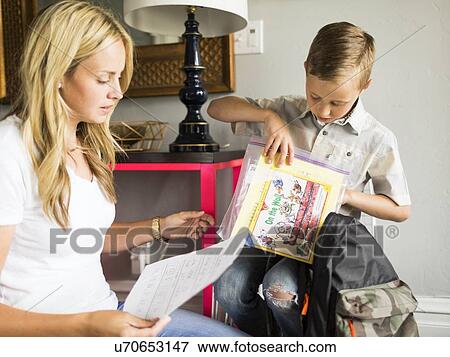 Stock Photo - Boy (6-7) showing schoolpaper to mother. Fotosearch