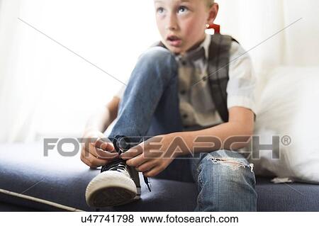 Stock Photo - Boy (6-7) tying shoes. Fotosearch