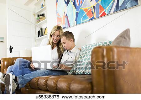 Stock Photography - Boy (6-7) with mother using laptop on sofa. Fotosearch