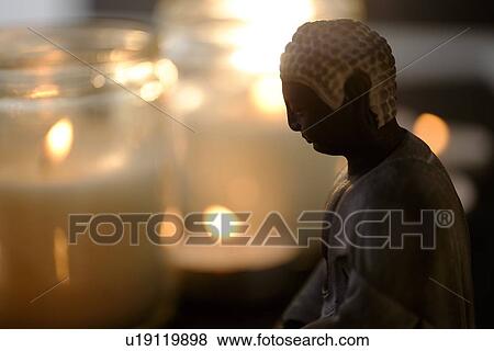 Burning candles with Buddha figurine in foreground View Large Photo Image Stock Photo - Burning candles with Buddha figurine in foreground. Fotosearch