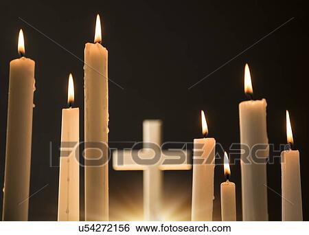 Stock Photograph - Burning candles with cross in background. Fotosearch
