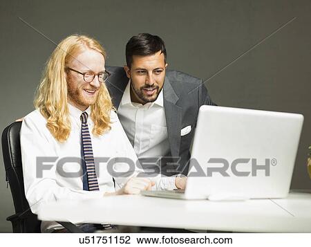 Businessmen looking at laptop in office View Large Photo Image Stock Image - Businessmen looking at laptop in office. Fotosearch